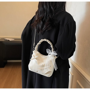 Detail view of cream white pleated cloud bag with lace bow and stylish ruched handle