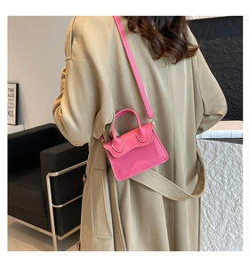 Mini sac en cuir rose rouge avec texture litchi porté par un mannequin en bureau moderne