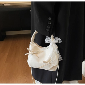 Close-up of white ruffled handle shoulder bag with large lace bow and shiny finish