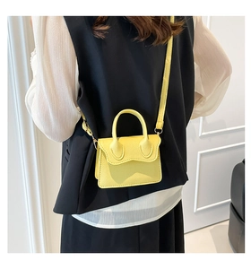 Nahaufnahme einer mini gelben Crossbody-Tasche aus Leder mit Litschi-Muster am Modell