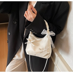 Detail of a creamy white cloud bag with lace bow decoration and matte leather finish