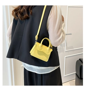 Mini sac bandoulière jaune chic avec texture litchi porté par un mannequin moderne