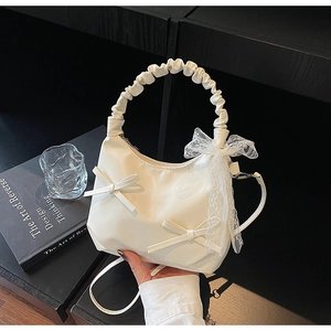 Detail of cream white crescent bag featuring lace ribbons and small bow decorations