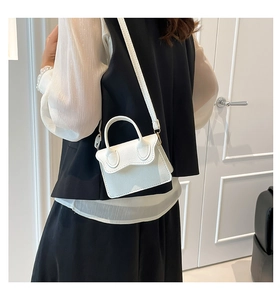 Mini sac à main blanc en cuir grainé avec poignée et bandoulière portées par le modèle