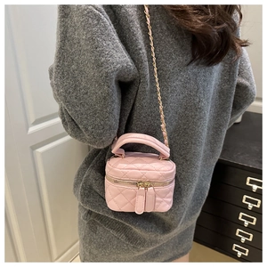 Detail of pink quilted mini vanity bag with gold chain strap on a model shoulder