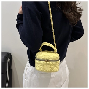 Detail of yellow quilted leather handbag with gold chain strap and top handle design