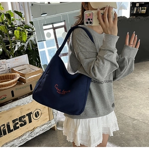 Close-up of navy canvas tote bag featuring red C'est lavie PAN'TOR embroidery detail