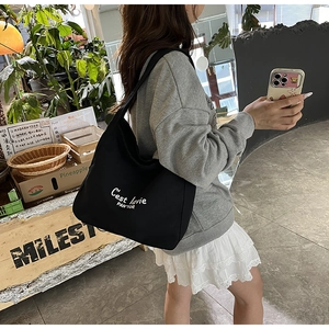 Detail of black canvas tote bag with 'C'est la vie' text styled with casual outfit
