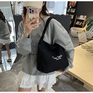 Detail of black canvas tote bag with artistic white lettering for daily fashion