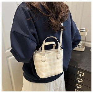 Close-up of a cream and yellow checkered small tote bag shown on a model's shoulder