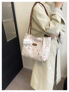 Close-up of quilted cream tote bag featuring pink floral bear prints and woven straps