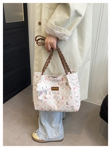 Detail of floral tote bag featuring a teddy bear print and a plush cloud charm accessory