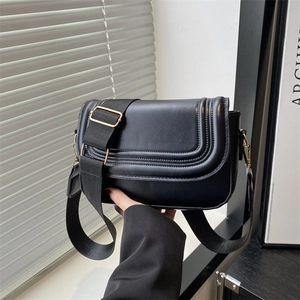 Classic black crossbody bag with triple stitching and wide strap in natural light