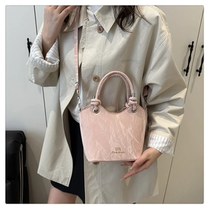 Detail of light pink bucket bag with marble texture and golden logo on beige coat