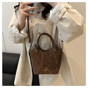 Detail of dark brown bucket bag featuring unique pleated texture and a long strap