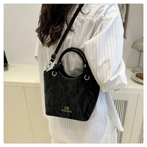 Close-up of black pleated texture bag with golden logo and elegant metallic hardware