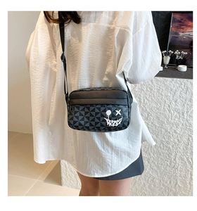 Detail of crossbody bag featuring geometric triangle patterns and graffiti smile face