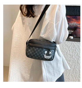 Model wearing dark grey crossbody bag with monster doodle and vintage geometric pattern