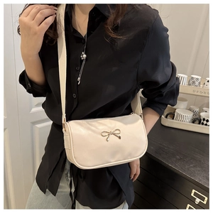 Detail of cream square handbag with gold bow buckle and wide canvas shoulder strap