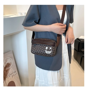 Detail of brown geometric crossbody bag featuring street art graffiti and wide strap