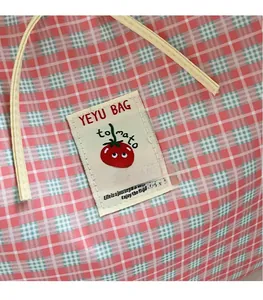 Dettaglio dell'etichetta in tessuto su una borsa tote in tela a quadretti rosa e bianchi
