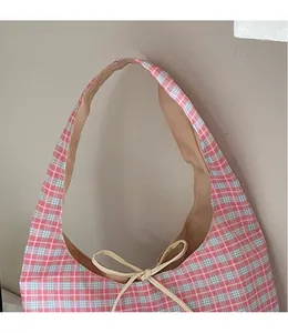 Dettaglio di una borsa tote in tela a quadretti rosa con coulisse e tracolla larga