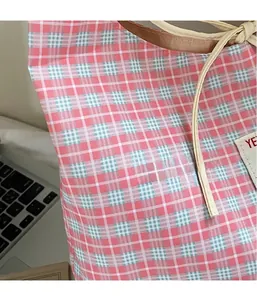 Dettaglio borsa in tela a scacchi rosa con etichetta YE e lacci di chiusura regolabili