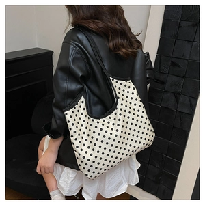Polka dot tote bag on shoulder shown with a stylish black leather jacket and white skirt