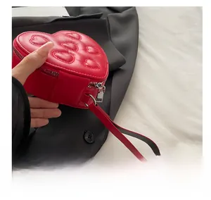 Detail of red heart-shaped shoulder bag featuring embossed patterns and metal zipper