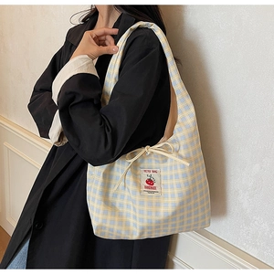 Dettaglio della borsa tote in tela a quadretti con patch pomodoro e fiocco su modella
