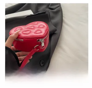 Detail of red heart-shaped handbag with quilted pattern and silver metal zipper