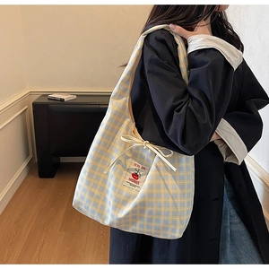 Detail of checkered canvas tote bag with tomato label and decorative drawstring bow