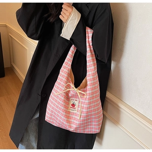 Detail of pink plaid tote bag featuring a tomato woven label and yellow drawstring accents