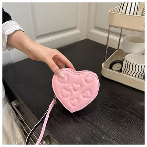 Detail of pink heart-shaped leather clutch bag with stitch patterns and wristlet