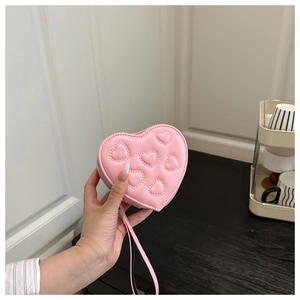 Detailed view of pink heart-shaped quilted coin purse with zipper and wrist strap