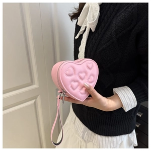 Detailed view of pink heart-shaped clutch with embossed pattern and wristlet strap