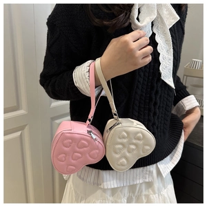Detail of heart-shaped quilted pouch with silver zipper and wrist strap in pink and beige