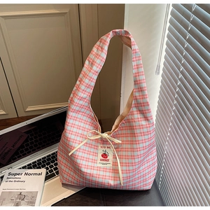 Dettaglio della borsa tote a quadri rosa con fiocco beige ed etichetta del marchio