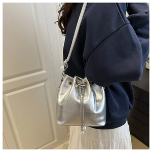Dettaglio della borsa a secchiello metallizzata argento con coulisse e perle eleganti