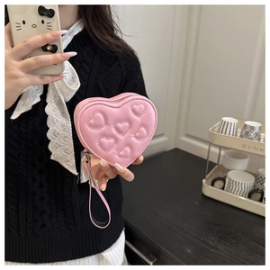 Dettaglio di borsa rosa a forma di cuore con trama trapuntata e cinturino in pelle
