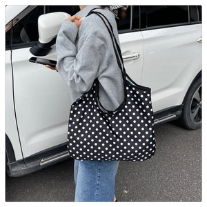 Sac fourre-tout en toile à pois porté à l'épaule sur un mannequin pour un look chic