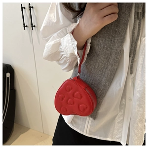 Close-up of a red heart-shaped mini purse with embossed patterns and wrist strap