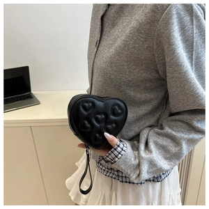 Detail of black heart-shaped handbag featuring quilted heart pattern and silver zipper