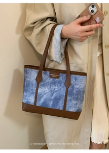 Detail of blue tie-dye denim and brown leather tote bag with elegant handles