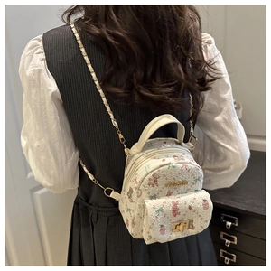 Detail of cute white floral mini backpack with pink bear pattern on a female model