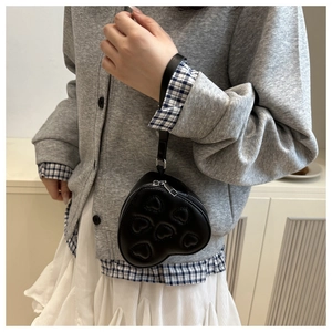 Detail of heart-shaped black PU leather coin purse with embossed pattern and metal zipper