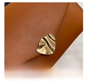 Détail de la texture en cuir marron et boucle dorée ondulée sur la pochette enveloppe