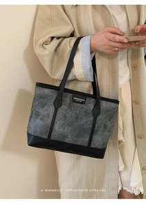 Detail of grey canvas tote with black leather trim worn with a beige trench coat