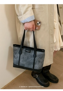 Detail of vintage style tote bag with leather straps and central fashion leather patch
