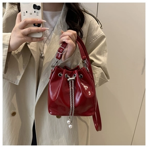 Dettaglio della borsa a secchiello in pelle rossa con catena e perle decorative